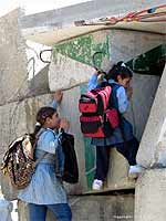 Two girls negotiate a low-point in the section of the Apartheid Wall near Abu Dis, in order to get to school on the other side.