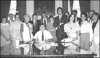 Supporters of the 'Rally Round the Quabbin Acid Rain Proclamation', August 1984, at the signing by Governor Michael Dukakis. Lt. Governor John Kerry stands behind Dukakis, and to Kerry's left is Genevieve Cora Fraser.