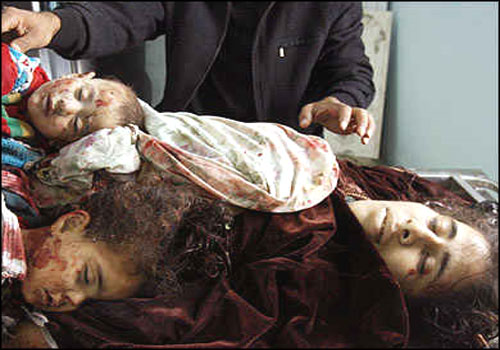 A Palestinian mother and her two babies lay together in the Beit Hanun hospital as morgue workers prepare the bodies for burial.